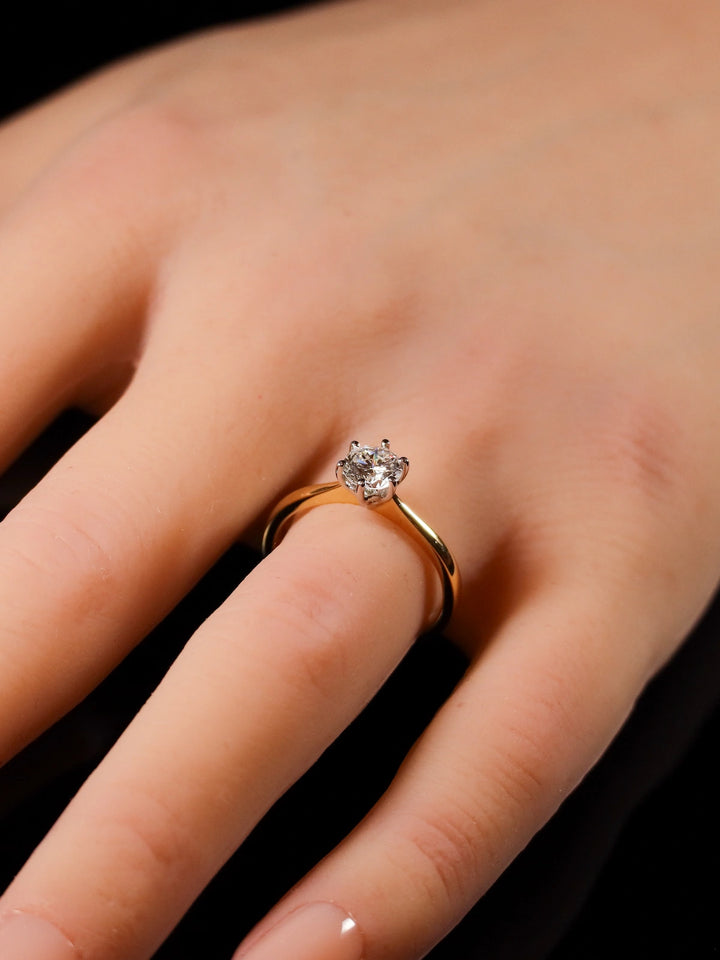 Close-up of a hand wearing the 18ct Yellow Gold Round Brilliant 0.70ct Diamond Solitaire Ring on the ring finger.