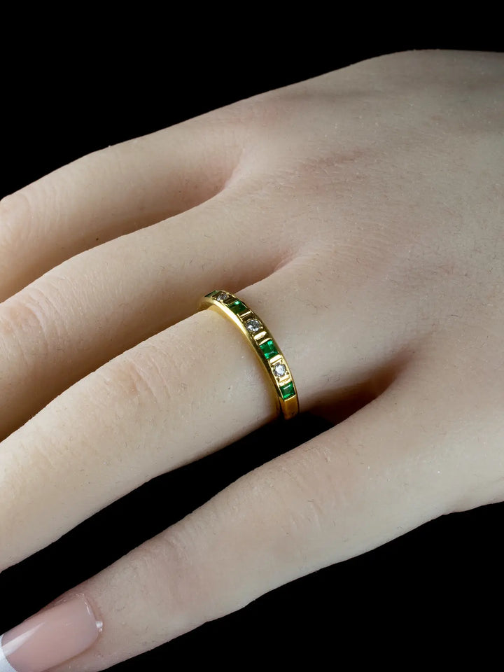Vintage 18ct Gold Emerald and Diamond Half Eternity Ring adorned on a finger against a black background.