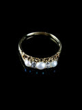 The Antique Victorian Seven Stone Pearl and Diamond Ring, Circa 1880 features three pearls and two small diamonds set against a dark backdrop.