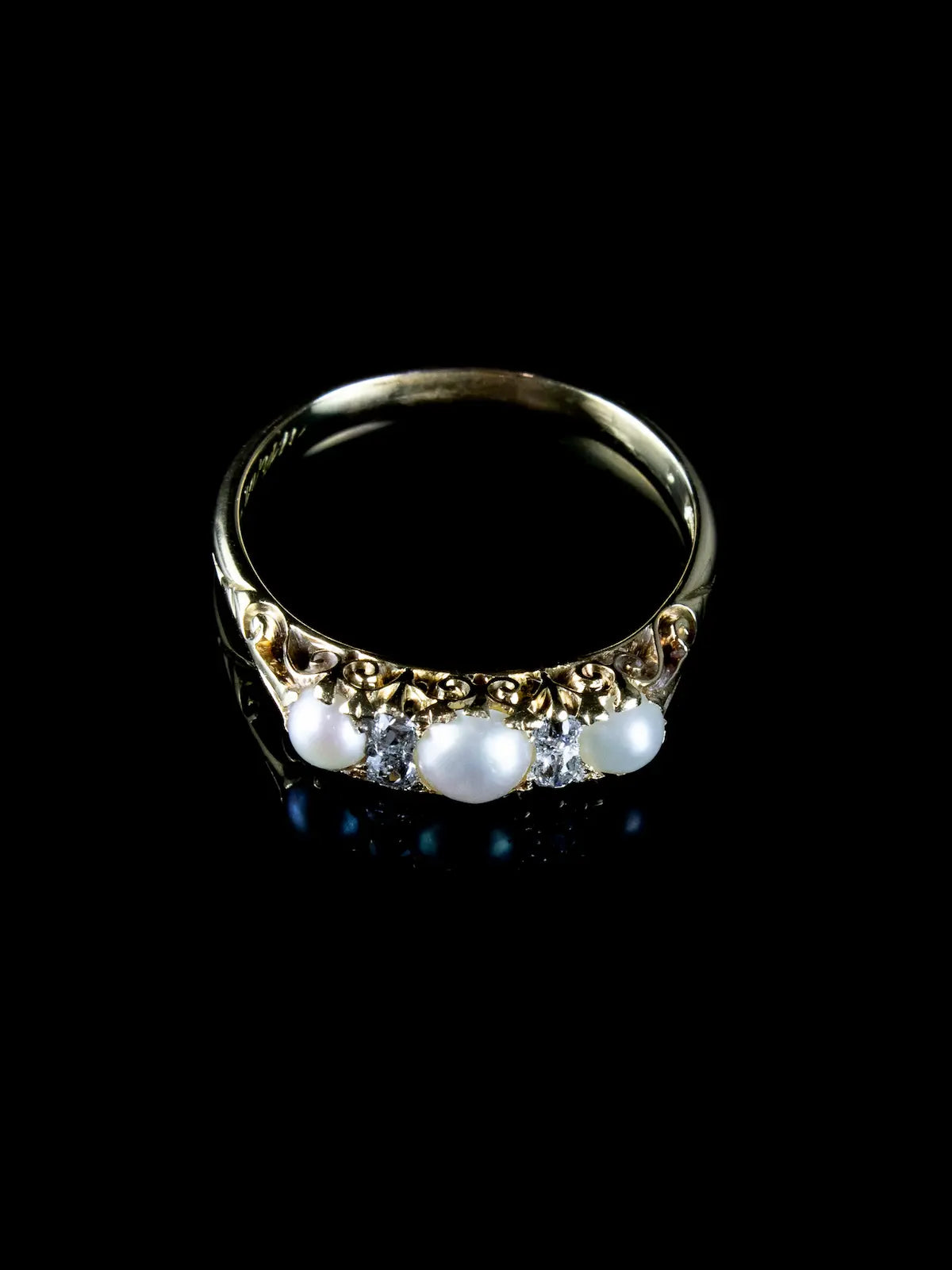 The Antique Victorian Seven Stone Pearl and Diamond Ring, Circa 1880 features three pearls and two small diamonds set against a dark backdrop.