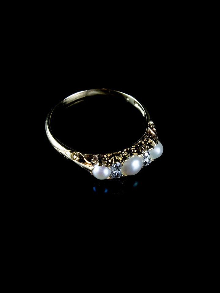 An Antique Victorian Seven Stone Pearl and Diamond Ring, Circa 1880, featuring three pearls and two clear gemstones, displayed on a black background.