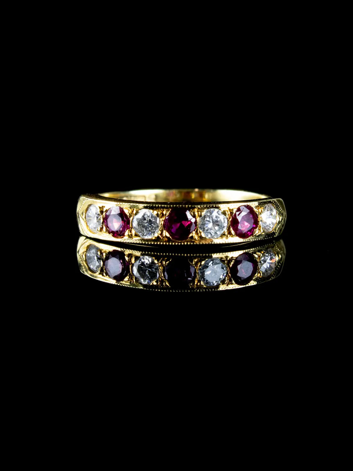 18ct gold ring featuring alternating rubies and diamonds glimmering on a black surface.