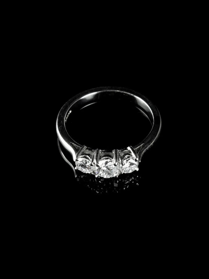 A platinum ring featuring three round diamonds against a dark backdrop.