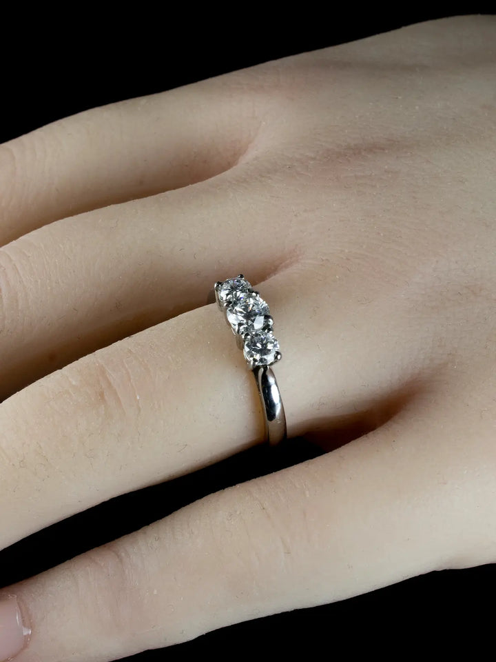 A hand wearing a Platinum Three Stone 0.92ct Diamond Ring on a black background.
