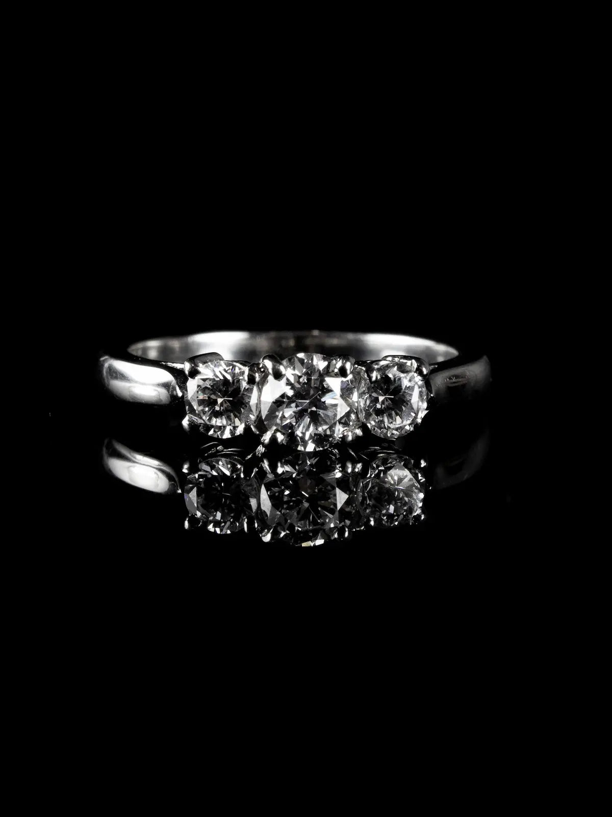 A platinum ring with three round diamonds totaling 0.92 carats, beautifully displayed on a black reflective surface.